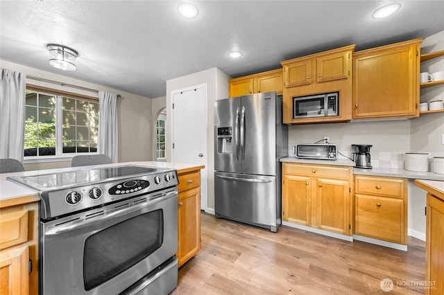 7605 38th Ct SE, Lacey, WA 98503 - kitchen featuring appliances with stainless steel finishes, light countertops, open shelves, light wood-type flooring, and arched walkways