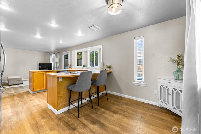 7605 38th Ct SE, Lacey, WA 98503 - kitchen featuring a peninsula, light wood-style floors, plenty of natural light, a kitchen bar, and recessed lighting