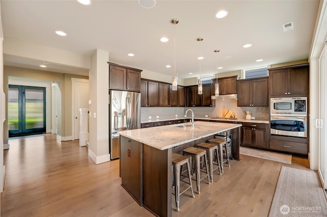 619 Graham Ave NE, Renton, WA 98059 - kitchen featuring appliances with stainless steel finishes, dark brown cabinets, backsplash, light wood-type flooring, and pendant lighting