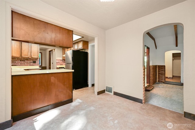 5510 Mt Baker Hwy, Deming, WA 98244 - kitchen with freestanding refrigerator, arched walkways, light countertops, a peninsula, and beamed ceiling
