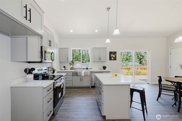 13540 Carney Lake Rd SW, Port Orchard, WA 98367 - kitchen with appliances with stainless steel finishes, light countertops, a breakfast bar area, gray cabinetry, and a kitchen island