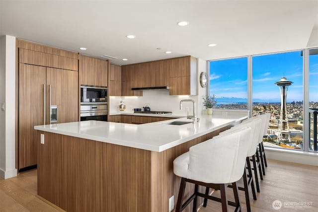 583 Battery St Unit 3802, Seattle, WA 98121 - kitchen with built in appliances, brown cabinetry, a peninsula, light countertops, and recessed lighting