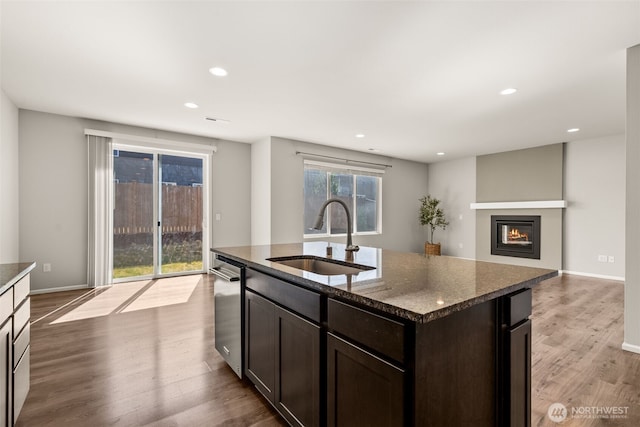 2846 Anna St NE, Lacey, WA 98516 - kitchen featuring dark brown cabinetry, wood finished floors, a glass covered fireplace, recessed lighting, and dark stone counters