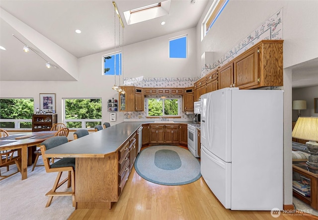 527 Fern Rd, Bellingham, WA 98225 - kitchen featuring white appliances, a high ceiling, a peninsula, brown cabinetry, and a skylight