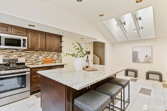17726 NE 26th St, Redmond, WA 98052 - kitchen with gas stove, a kitchen island, a breakfast bar area, backsplash, and vaulted ceiling