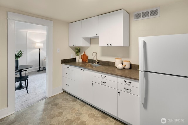 5041 Baker Ave NW, Seattle, WA 98107 - kitchen featuring freestanding refrigerator, dark countertops, white cabinetry, and light carpet