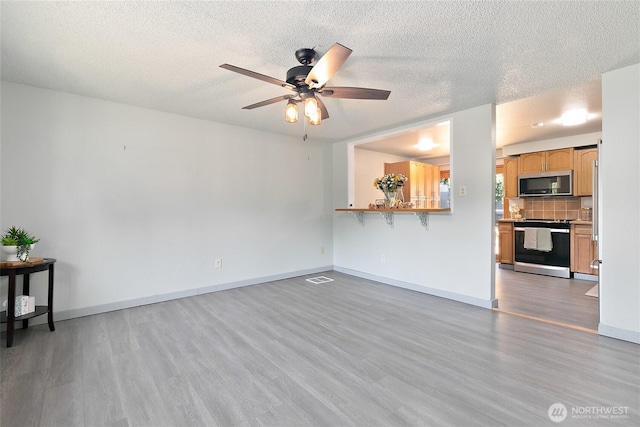 5701 38th Ct SE, Lacey, WA 98503 - unfurnished living room featuring wood finished floors, a ceiling fan, and a textured ceiling