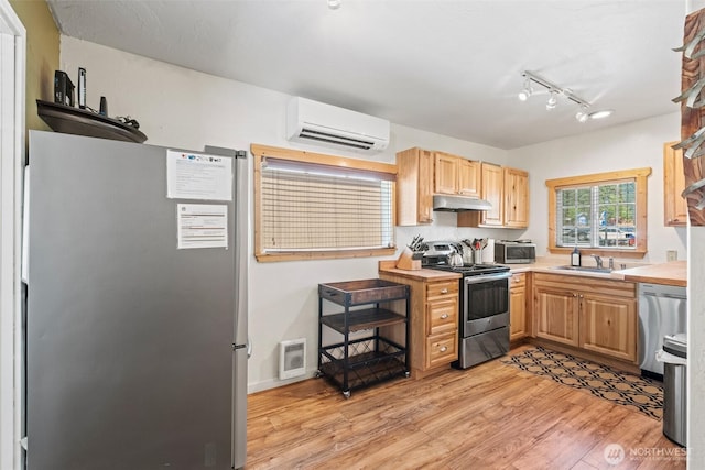 1313 Front St, Leavenworth, WA 98826 - kitchen with stainless steel appliances, a wall mounted air conditioner, under cabinet range hood, light countertops, and light brown cabinets