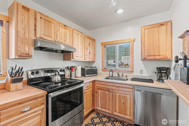 1313 Front St, Leavenworth, WA 98826 - kitchen with appliances with stainless steel finishes, under cabinet range hood, light brown cabinetry, and butcher block counters