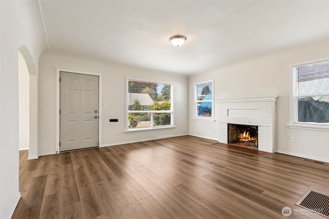 3154 Pear St SE, Olympia, WA 98501 - unfurnished living room with healthy amount of natural light, wood finished floors, a brick fireplace, and arched walkways