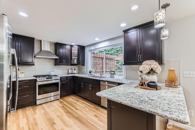14111 NE 63rd Ct, Redmond, WA 98052 - kitchen featuring wall chimney exhaust hood, appliances with stainless steel finishes, a peninsula, light wood-style flooring, and decorative backsplash