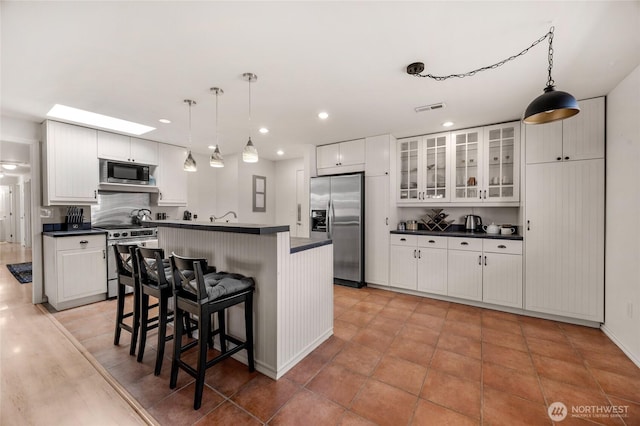 8851 48th Pl W, Mukilteo, WA 98275 - kitchen with stainless steel appliances, dark countertops, a center island with sink, a breakfast bar area, and recessed lighting