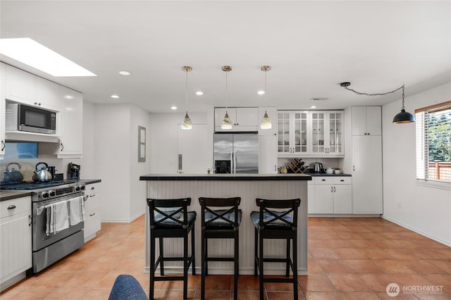 8851 48th Pl W, Mukilteo, WA 98275 - kitchen with appliances with stainless steel finishes, dark countertops, a kitchen breakfast bar, white cabinets, and recessed lighting