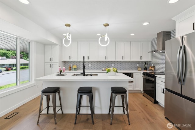 2204 139th Pl SE, Bellevue, WA 98005 - kitchen featuring appliances with stainless steel finishes, wall chimney range hood, a breakfast bar, tasteful backsplash, and recessed lighting