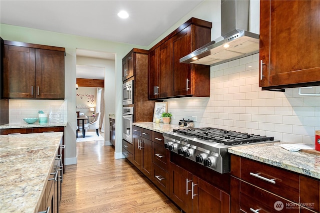8019 149th Pl SE, Newcastle, WA 98059 - kitchen with wall chimney exhaust hood, appliances with stainless steel finishes, decorative backsplash, light stone counters, and light wood-type flooring
