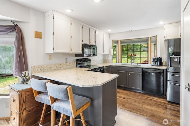 16714 Broadway Ave, Snohomish, WA 98296 - kitchen with black appliances, white cabinets, a peninsula, wood finished floors, and recessed lighting