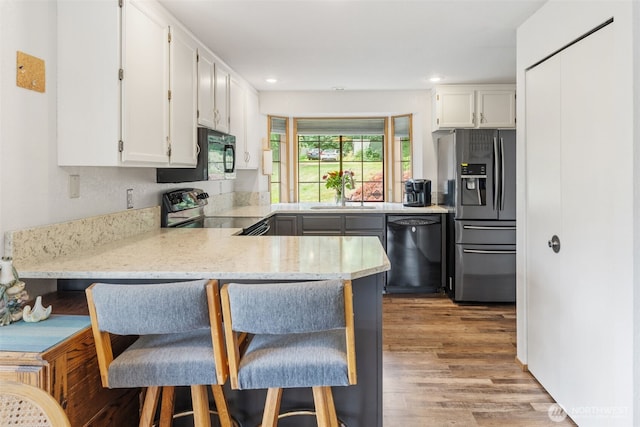 16714 Broadway Ave, Snohomish, WA 98296 - kitchen featuring black appliances, a peninsula, white cabinets, light wood-style floors, and recessed lighting