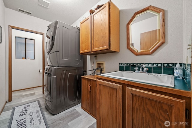 16714 Broadway Ave, Snohomish, WA 98296 - laundry area featuring stacked washer and clothes dryer, cabinet space, and light wood-type flooring