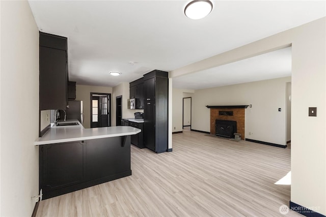 136 D St, Buckley, WA 98321 - kitchen with light countertops, dark cabinetry, open floor plan, freestanding refrigerator, and light wood finished floors
