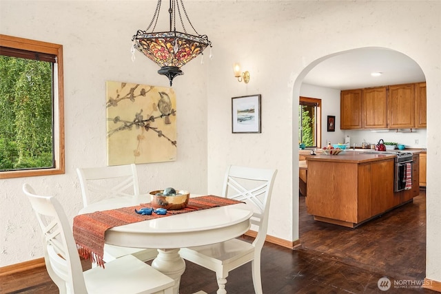 10634 SW Cowan Rd, Vashon, WA 98070 - dining room with arched walkways, a textured wall, and dark wood-type flooring