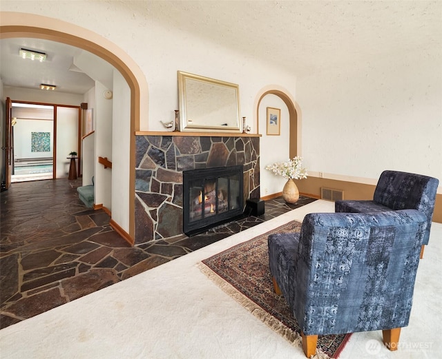 10634 SW Cowan Rd, Vashon, WA 98070 - living area with stone flooring, a stone fireplace, and arched walkways