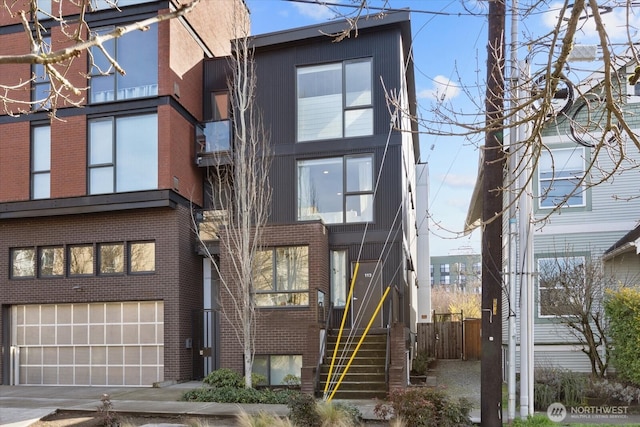 4422 Woodlawn Ave N Unit 213, Seattle, WA 98103 - view of front of house featuring an attached garage, stairs, brick siding, and driveway