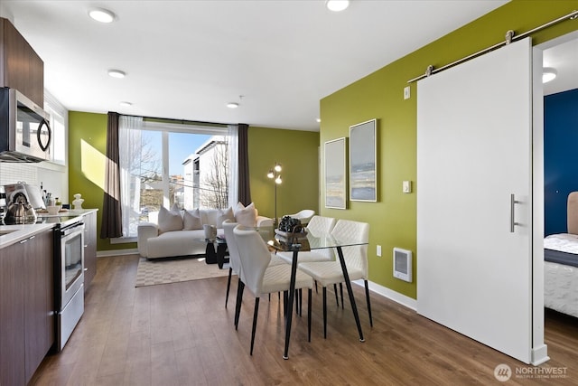 4422 Woodlawn Ave N Unit 213, Seattle, WA 98103 - dining space featuring a barn door, wood finished floors, heating unit, and recessed lighting