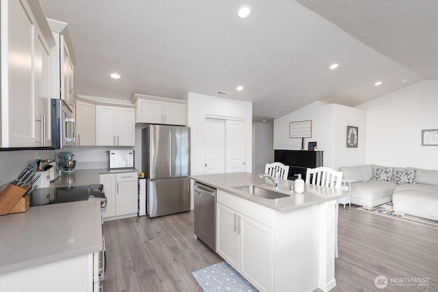 1205 W Sequoia Rd, Moses Lake, WA 98837 - kitchen with stainless steel appliances, light wood-style floors, white cabinets, vaulted ceiling, and open floor plan