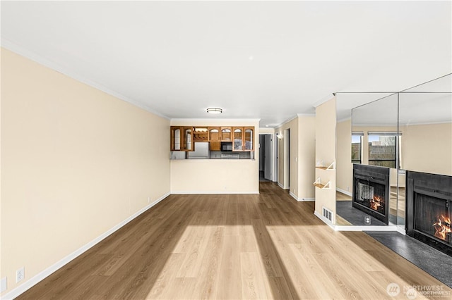 500 W Roy St Unit 102, Seattle, WA 98119 - unfurnished living room with a multi sided fireplace, wood finished floors, and ornamental molding