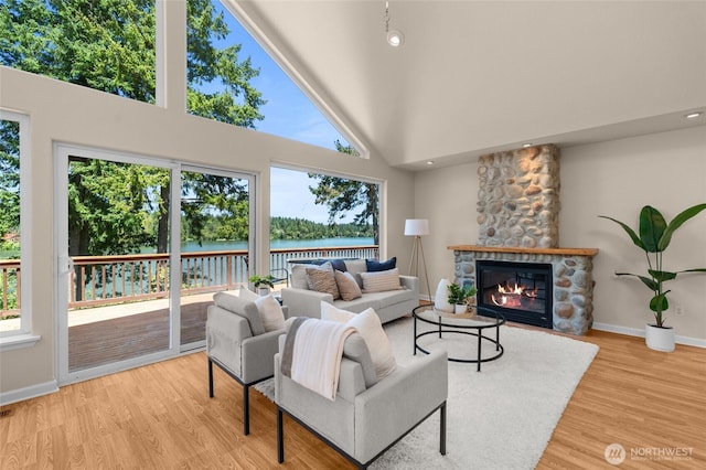 21945 Promontory Ct SE, Yelm, WA 98597 - living area with a water view, a towering ceiling, light wood-style flooring, and a stone fireplace