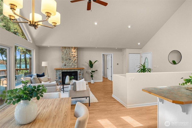 21945 Promontory Ct SE, Yelm, WA 98597 - living room with high vaulted ceiling, ceiling fan, a fireplace, light wood-style floors, and a chandelier