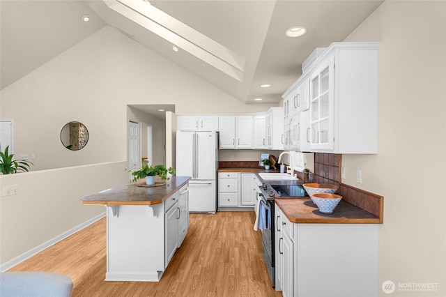21945 Promontory Ct SE, Yelm, WA 98597 - kitchen with freestanding refrigerator, range with electric stovetop, a skylight, white cabinetry, and light wood-type flooring