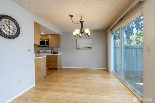 2913 27th St SE, Auburn, WA 98092 - kitchen with stainless steel microwave, a textured ceiling, brown cabinetry, light wood-style flooring, and light countertops