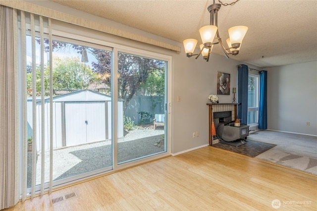 2913 27th St SE, Auburn, WA 98092 - unfurnished living room with a wood stove, a chandelier, a textured ceiling, and wood finished floors