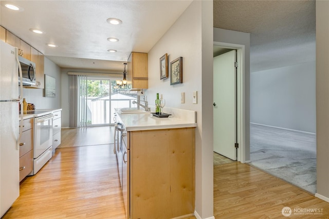 2913 27th St SE, Auburn, WA 98092 - kitchen with white appliances, light wood finished floors, recessed lighting, light countertops, and a chandelier