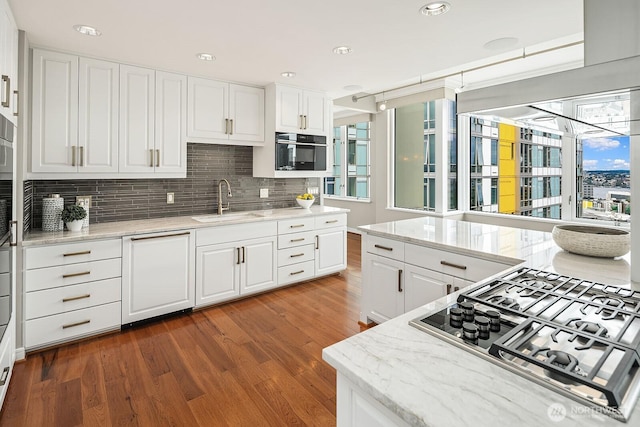 2600 2nd Ave Unit 2501, Seattle, WA 98121 - kitchen featuring stainless steel gas stovetop, dishwasher, wood finished floors, backsplash, and white cabinets