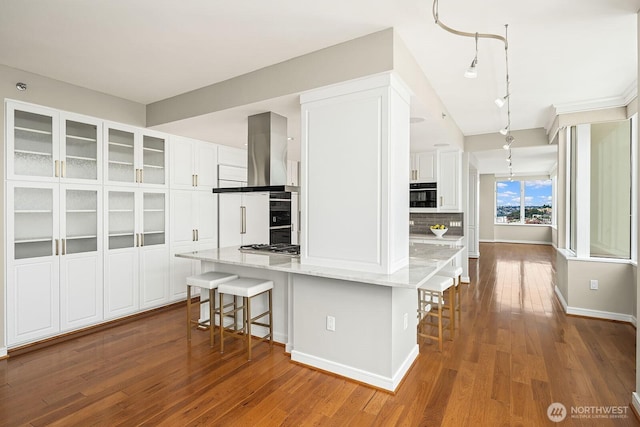 2600 2nd Ave Unit 2501, Seattle, WA 98121 - kitchen with wall chimney exhaust hood, white cabinetry, a kitchen bar, and backsplash