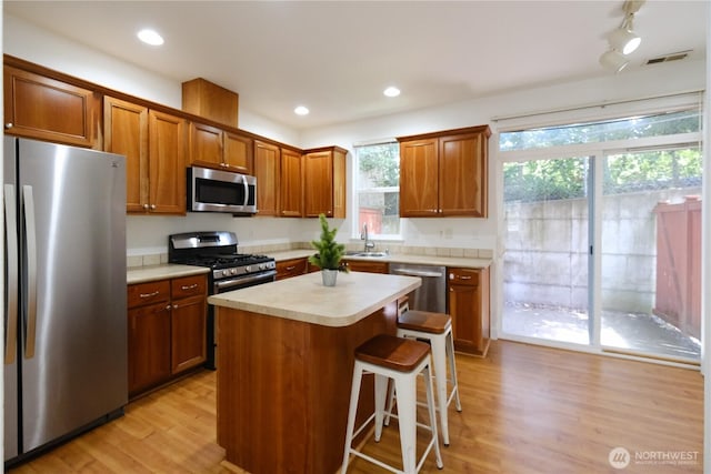 28710 S 34th Ave Unit B5, Auburn, WA 98001 - kitchen with appliances with stainless steel finishes, light countertops, light wood finished floors, a breakfast bar, and brown cabinetry