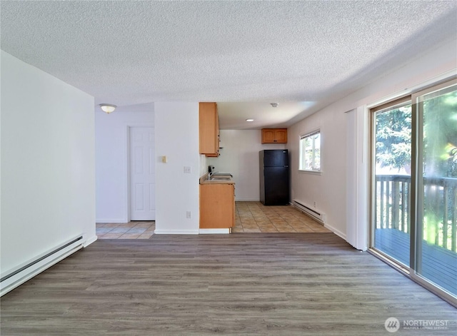 2716 S 256th Pl, Kent, WA 98032 - unfurnished living room featuring a baseboard heating unit, a textured ceiling, and light wood finished floors