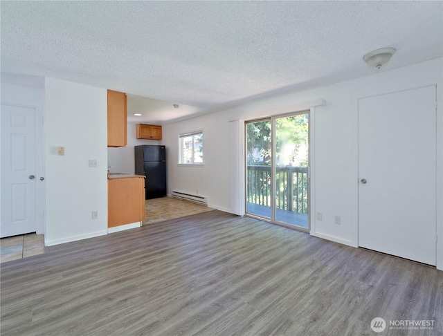 2716 S 256th Pl, Kent, WA 98032 - unfurnished living room with a baseboard heating unit, light wood finished floors, and a textured ceiling