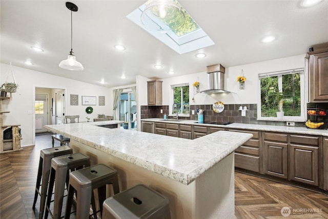 29 Sherburne Rd, Sequim, WA 98382 - kitchen with a skylight, wall chimney exhaust hood, a breakfast bar area, vaulted ceiling, and tasteful backsplash