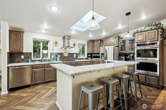 29 Sherburne Rd, Sequim, WA 98382 - kitchen featuring appliances with stainless steel finishes, wall chimney exhaust hood, a skylight, a kitchen island, and plenty of natural light