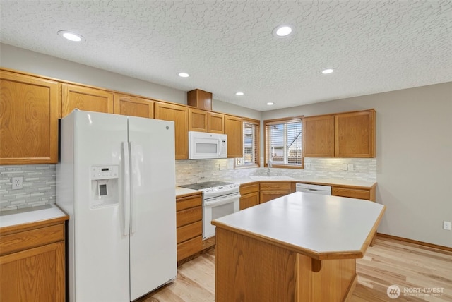 13019 NE 96th Way, Vancouver, WA 98682 - kitchen featuring white appliances, light wood finished floors, a kitchen island, a textured ceiling, and tasteful backsplash