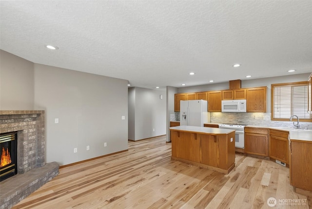 13019 NE 96th Way, Vancouver, WA 98682 - kitchen featuring white appliances, a center island, light wood-type flooring, light countertops, and backsplash