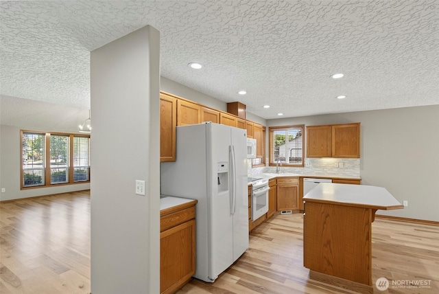 13019 NE 96th Way, Vancouver, WA 98682 - kitchen featuring white appliances, light wood finished floors, light countertops, a center island, and a textured ceiling