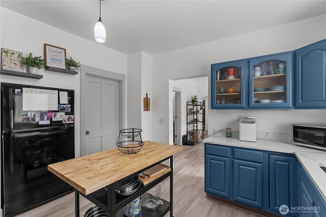 3738 E J St, Tacoma, WA 98404 - kitchen with freestanding refrigerator, blue cabinets, stainless steel microwave, and light countertops
