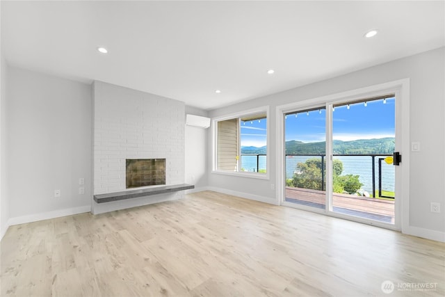 610 Northshore Dr Unit 6123, Bellingham, WA 98226 - unfurnished living room with wood finished floors, a fireplace, recessed lighting, a wall mounted air conditioner, and a water view