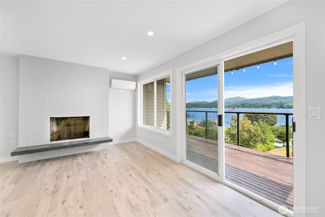 610 Northshore Dr Unit 6123, Bellingham, WA 98226 - unfurnished living room featuring a water and mountain view, wood finished floors, a wall mounted AC, a brick fireplace, and recessed lighting