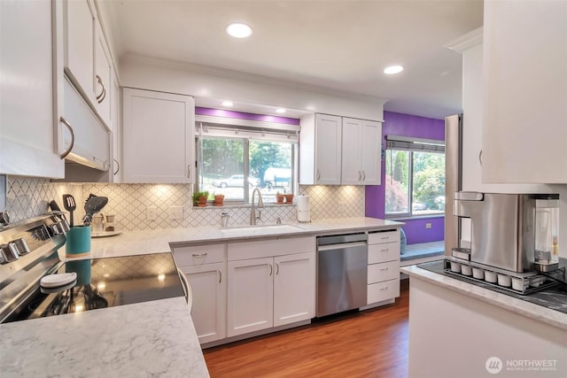 1515 NE 106th St, Seattle, WA 98125 - kitchen with stainless steel appliances, white cabinets, decorative backsplash, light wood-style floors, and ornamental molding
