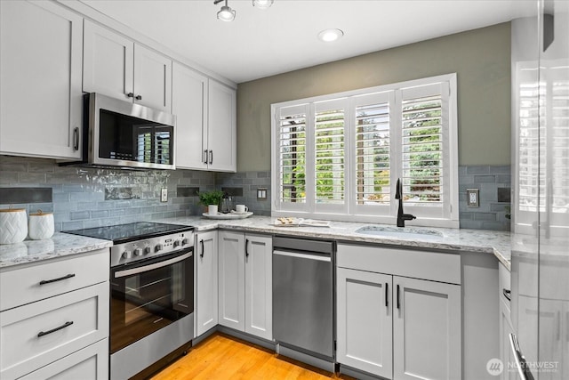 728 NW 189th Ln, Shoreline, WA 98177 - kitchen with appliances with stainless steel finishes, tasteful backsplash, light wood-style floors, and light stone countertops